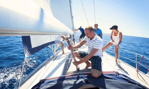 Sailboat on ocean with people setting up the sails.