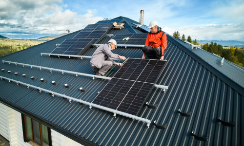 Two people mounting solar panels on a roof.