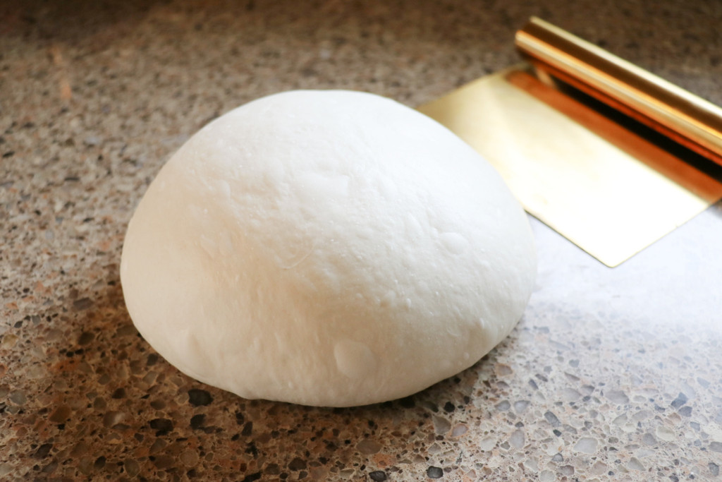 Boule with gold dough scraper in the sun on granite countertop