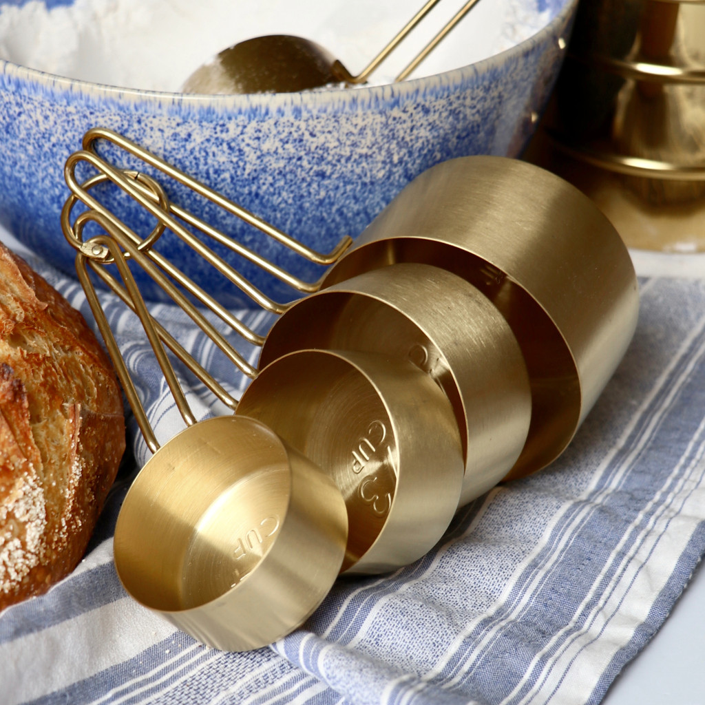 Nested measuring cups with bowl of flour and fresh bread on kitchen counter