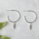 Silver hoop earrings with leaf charm.