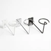 Three wire cap holders with looped cradles and gridwall back plates in white, chrome, and black finishes