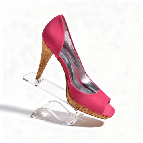 Clear acrylic curled heel rest displaying a pink peep-toe shoe with cork wedge heel.