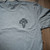 Lifestyle photo of the front of the Men's Deer Tee - Dark Heather Grey on a table. Product sold by Midwest Industries. Shop all Apparel.