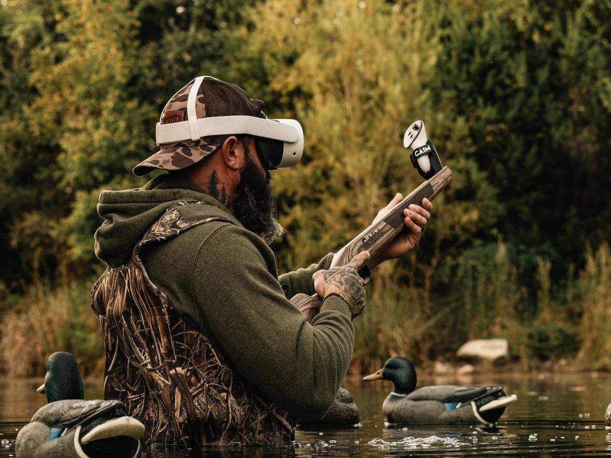 Hunter in waders training with GAIM beside duck decoys