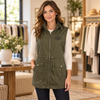 Woman wearing an olive green monogrammed utility vest with a drawstring waist and front patch pockets in a boutique.