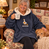 An older woman wearing an embroidered knitting hoodie blanket in a cozy home