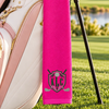 pink golf towel with a black KGS shield monogram, crossed golf clubs, and silver golf ball hanging from a golf bag.