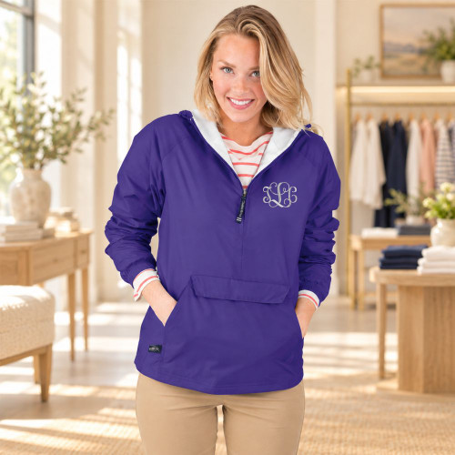 Woman wearing a purple pullover jacket with a partial zipper and front pouch pocket in a softly lit boutique.