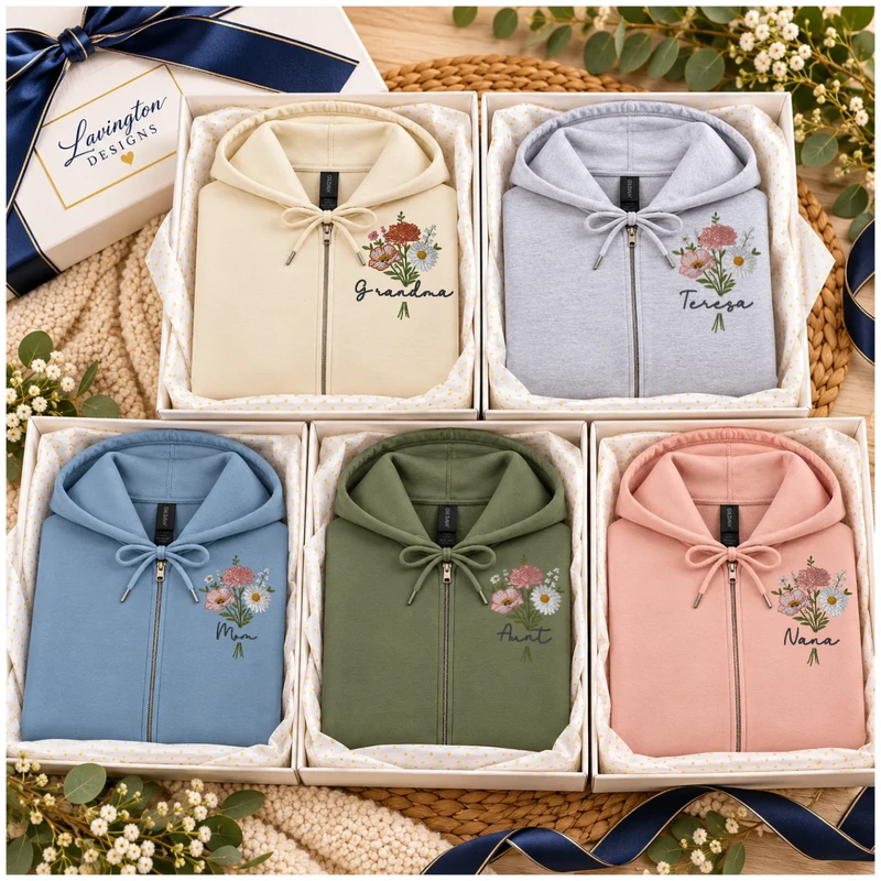 Five personalized floral embroidered zip-up hoodies in cream, grey, blue, green, and pink arranged in gift boxes
