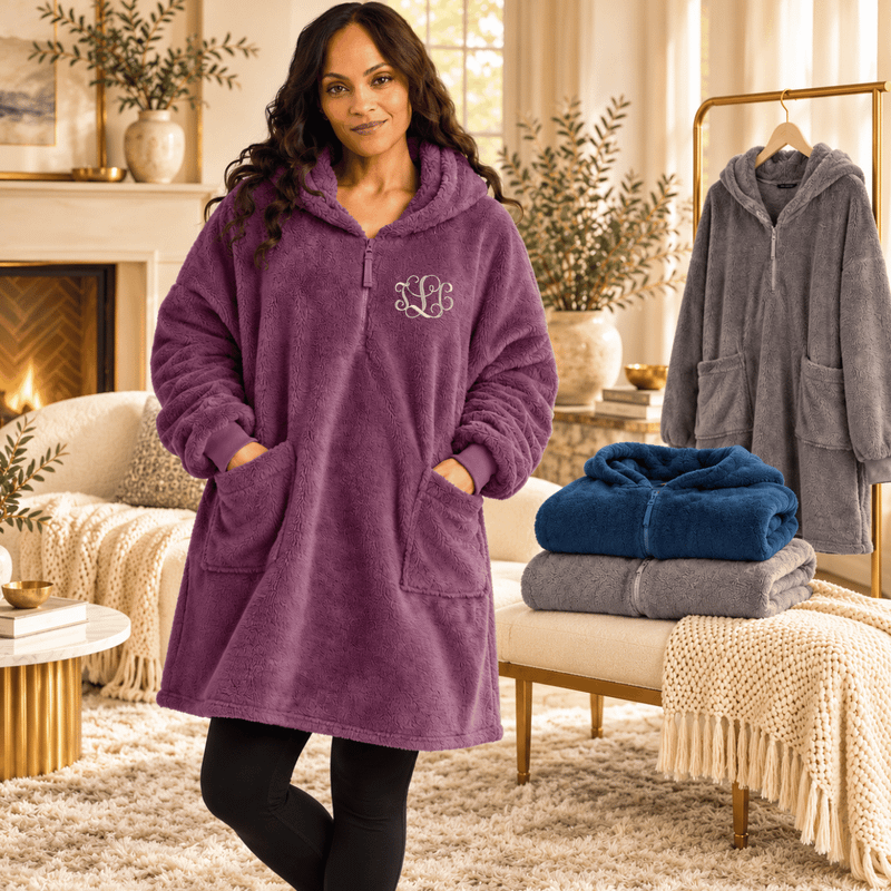 Three plush fleece ponchos hanging in a boutique display in Smoke Grey, River Blue Navy, and Deep Purple Mist.