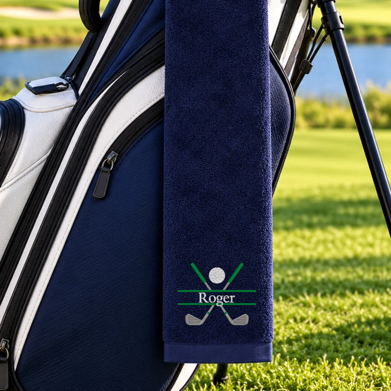 Navy golf towel embroidered with Roger, green crossed golf clubs, and a silver golf ball hanging from a golf bag.