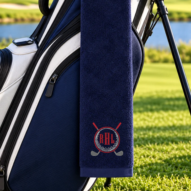 Navy golf towel with a red RHL monogram inside a silver golf ball design, red border, and crossed golf clubs.