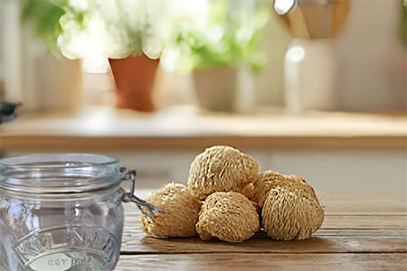 Fresh lion's mane mushrooms spread on a wooden kitchen surface beside a mason storage jar