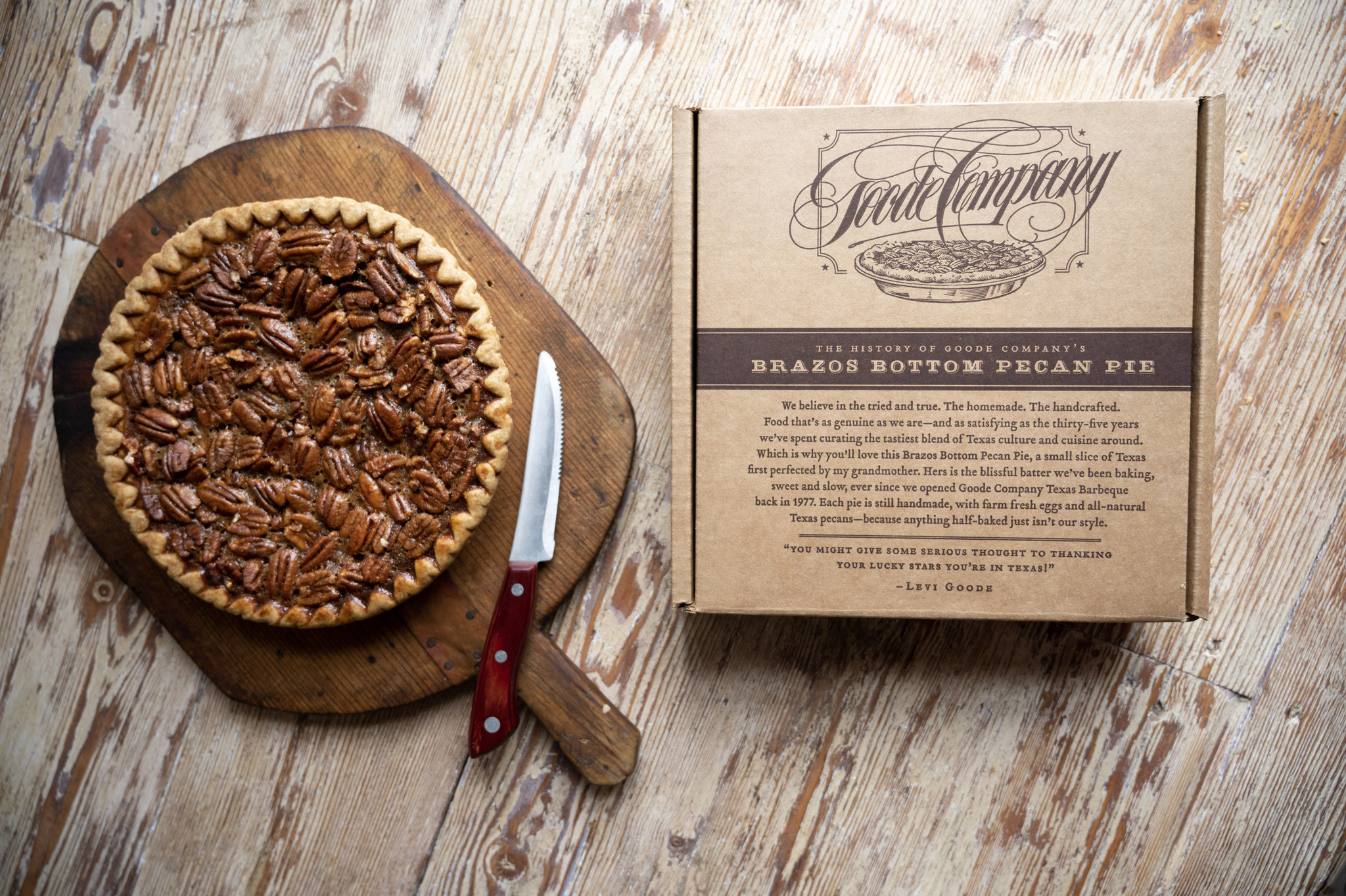 Brazos Bottom Pecan Pie with a knife next to it. To the right is a cardboard box with the Goode Company logo and a note about the pecan pie.