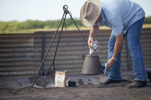 Levi Goode preparing chuckwagon style coffee over fire pit.