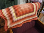 Angled view of the Pink Sunset handmade crochet blanket showing its textured waffle stitch and concentric square design