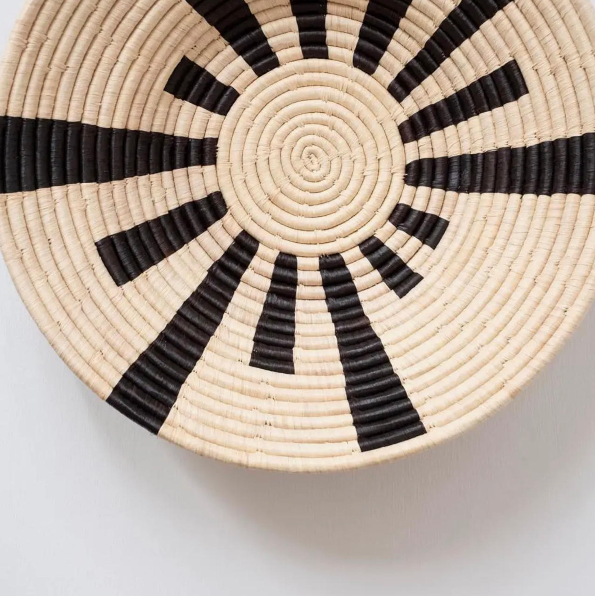 Large Warp Speed Basket - A stunning collection of baskets on display or elevate your tablescape with a unique centerpiece. A simple yet bold basket from our Black & Natural collection. Handcrafted by women artisans living in Central Uganda who are part of a cooperative that provides employment and training for disadvantaged or marginalized communities - particularly widows, the disabled and those living with HIV/AIDS.

* Made from all natural, sustainably sourced raffia and banana fibers * All synthetic AZO free dyes * Hanging loop on back allows basket to be wall decor in addition to tabletop use * Weavers hand make each basket from home while tending to other household duties | Details: Made in Uganda • Dimensions: 18″ x 18″ x 5″ (45.7 x 45.7 x 12.7 cm) • Weight: 2.5 lb (1.1 kg)