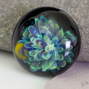 Fluid flowing greens and deep purple in elongated petals. The cabochon is  highly textured. Due to its darker coloring it needs to be seen in bright light to truly appreciate it's wonder. 26mm