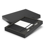 A black gift box containing a dark grey notebook and a silver pen. The notebook includes a section for notes.