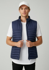 A man is wearing a navy blue vest over a white t-shirt, featuring a logo on the upper left.