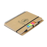 A kraft notebook with a spiral binding, featuring coloured sticky flags and two pens. It has a logo on the cover.
