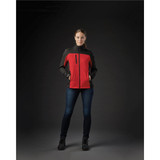A woman wearing a red and black softshell jacket with pockets, standing against a dark background.