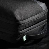 A black backpack with a textured exterior and a mint green zipper pull, featuring a side handle.