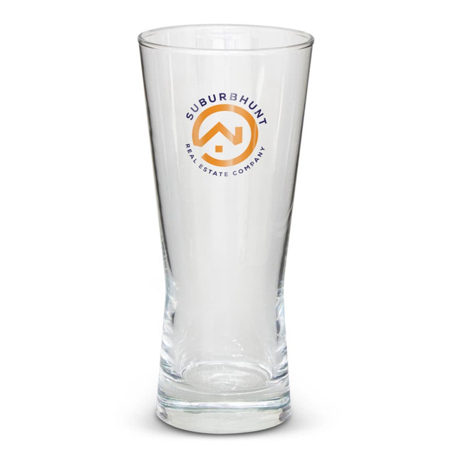 A tall, clear beer glass with a branding logo. The glass features a tapered design.