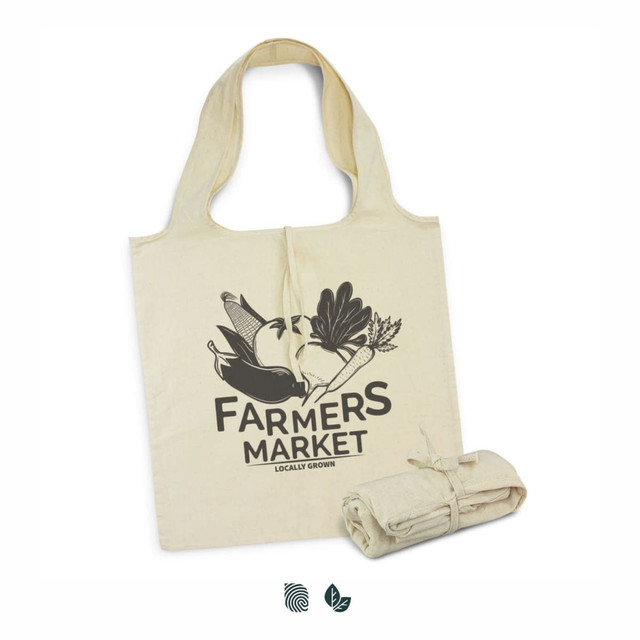 A cream-coloured foldaway tote bag featuring a graphic design and a logo, neatly rolled and tied next to it.
