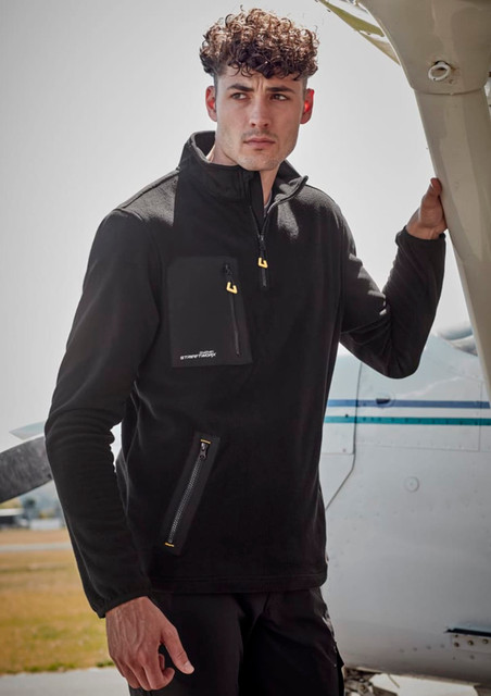 A model wearing a black unisex lightweight 1/4 zip polar fleece with a front pocket, standing next to an aircraft.