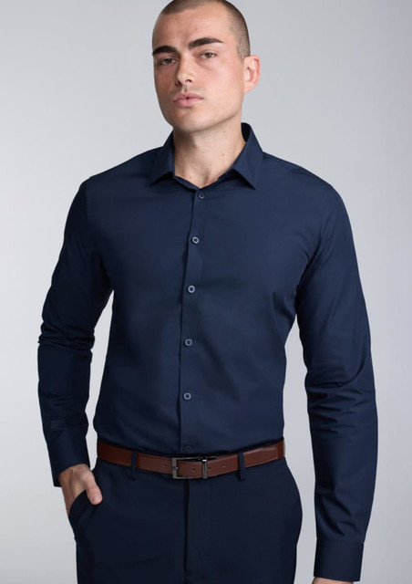 A fitted long sleeve shirt in navy blue, featuring a button-up front and a sleek collar, worn by a model.
