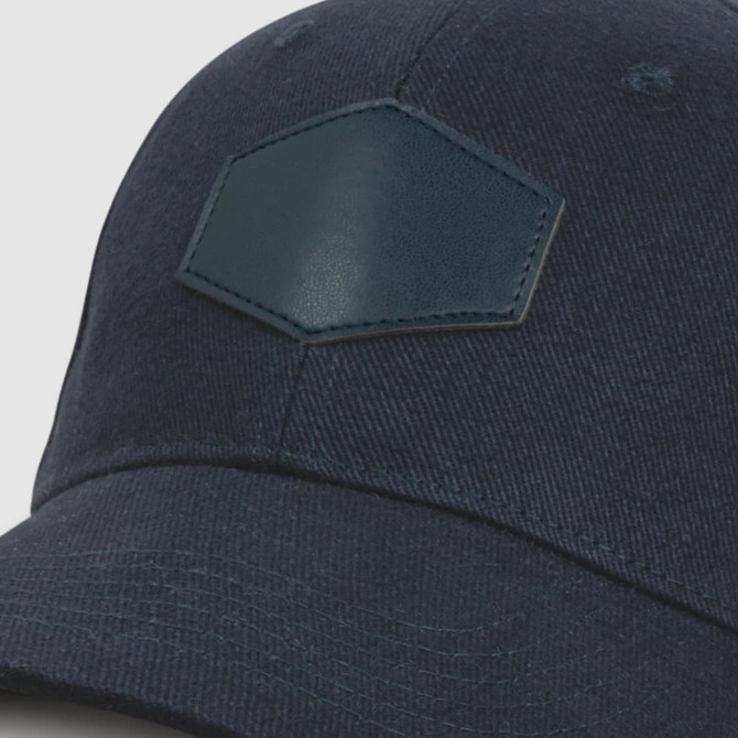 A navy cap featuring a leather patch, designed with a structured brim and a classic style.