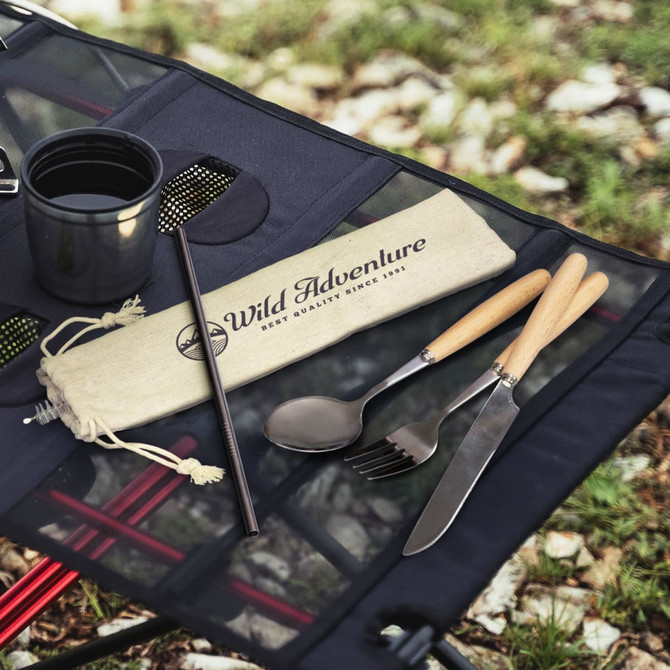 A stainless steel cutlery set with wooden handles, including a spoon, fork, knife, and straw, in a cloth pouch.