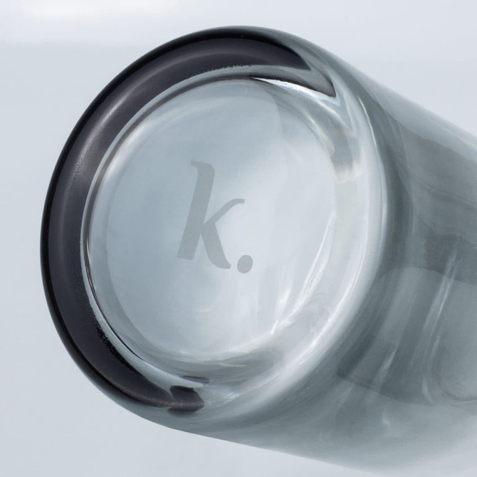 A glass carafe with a dark rim and a logo at the base, showcasing a sleek and modern design.