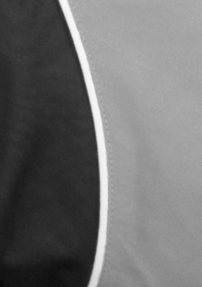 A black and grey short sleeve shirt featuring a curved design and contrast piping, with a logo displayed.