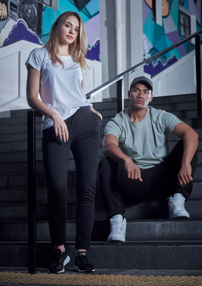 A woman in a white T-shirt and a man in a grey T-shirt sit on black stairs, both wearing casual athletic attire.