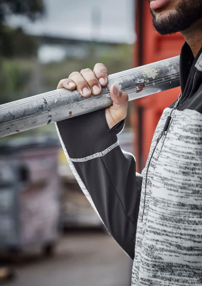 A person holding a metal pole wears a grey and black reinforced knit hoodie with a logo.
