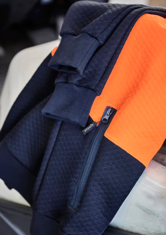 A textured jacquard hoodie featuring navy and orange colours, with a front zip pocket and a logo.