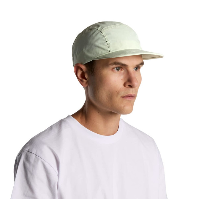 A light green nylon cap with a flat brim, featuring a logo, worn by a model in a white t-shirt.