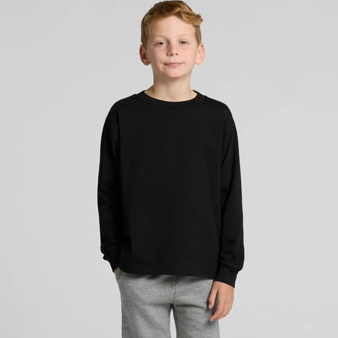 A child wearing a black long-sleeve T-shirt, paired with grey trousers, posing against a plain background.