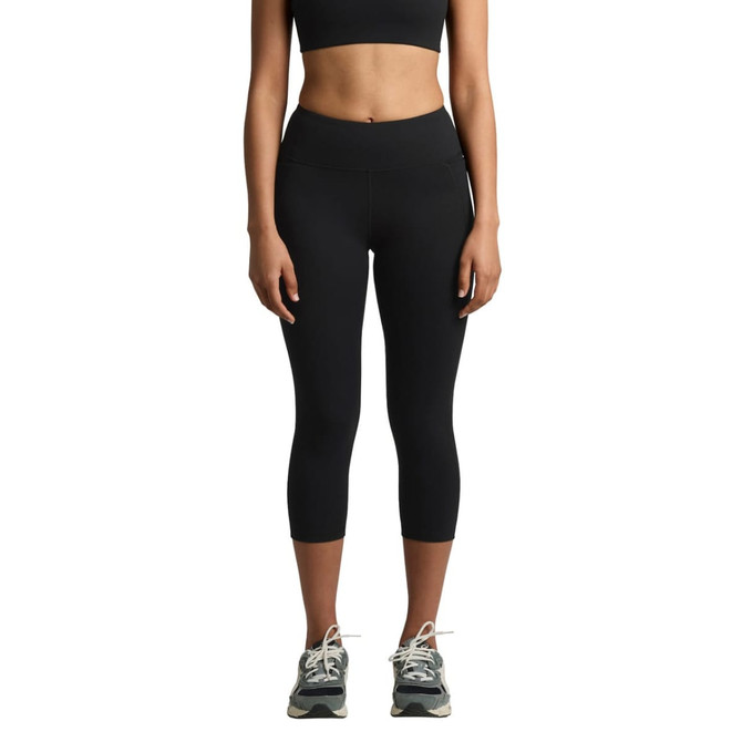 A pair of black mid-length leggings, featuring a fitted design and a subtle logo, worn with athletic shoes.