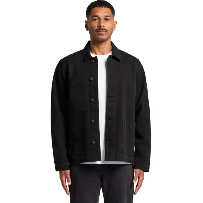 A man wearing a black canvas chore jacket with front pockets, styled over a white t-shirt.