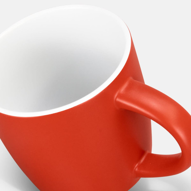 A red coffee mug with a matte finish and a white interior, featuring a handle and a branding logo.