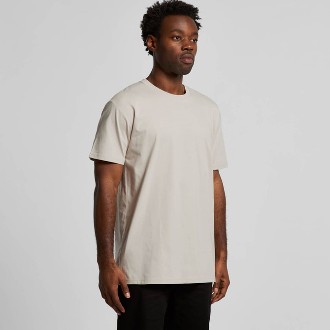 A plain beige T-shirt displayed on a model, featuring a round neckline and short sleeves. It has a brand logo.