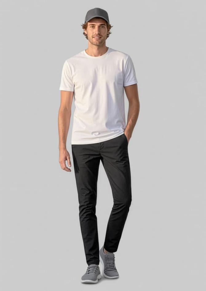 A man wearing black Venture Pants and a white t-shirt, with a grey cap and shoes, standing against a plain background.