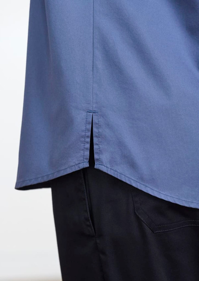 A blue short sleeve chef shirt with a split hem, paired with dark trousers, featuring a logo.