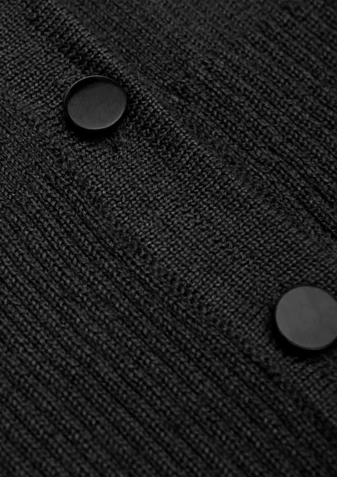 A close-up of a black cardigan featuring textured fabric and two round buttons.