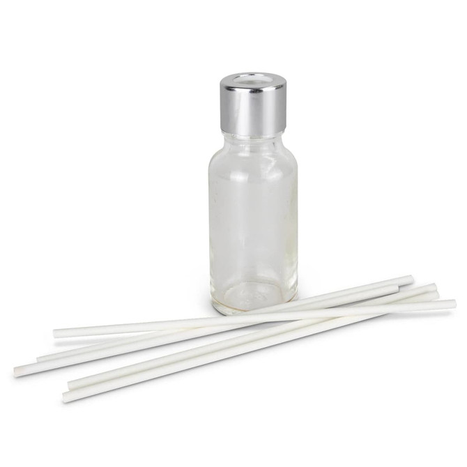 A glass scented diffuser bottle with a silver lid and five white reeds arranged beside it.