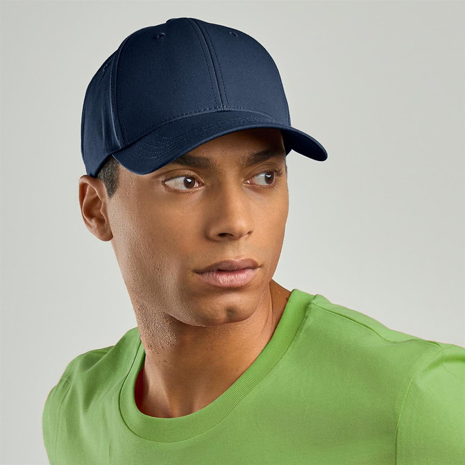 A navy cap with a structured design, worn by a model in a green T-shirt. The cap features a logo.